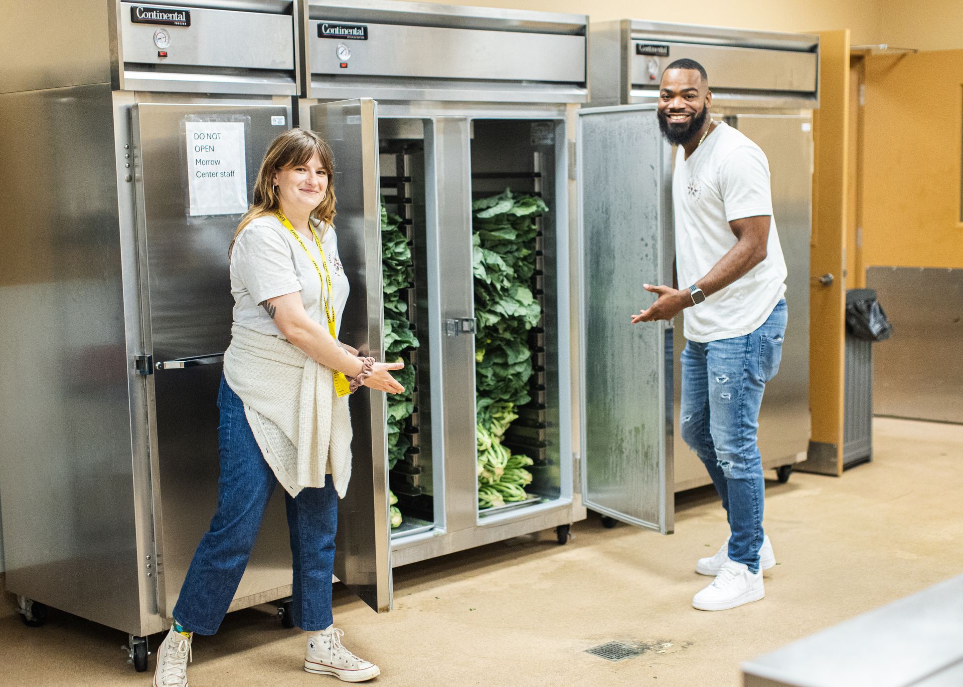 A man and a woman are standing in front of a refrigerator in a kitchen.