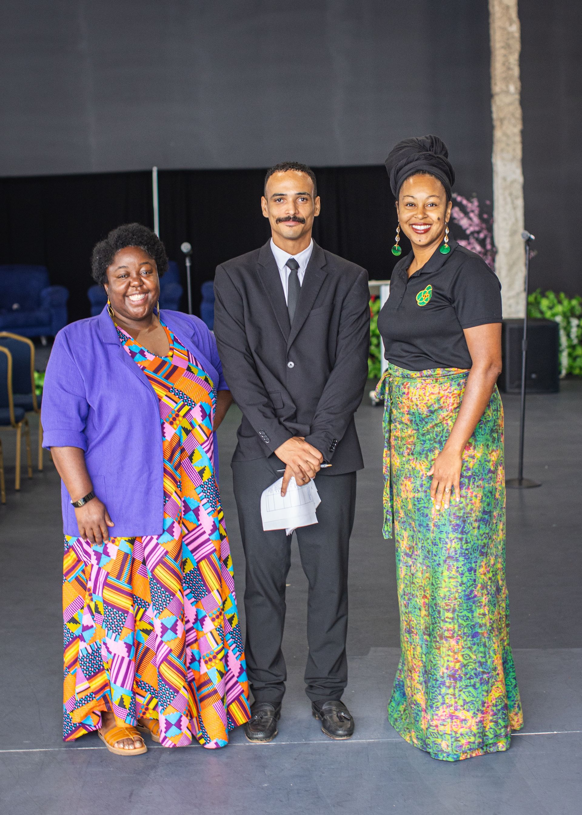 A man and two women are standing next to each other in a room.