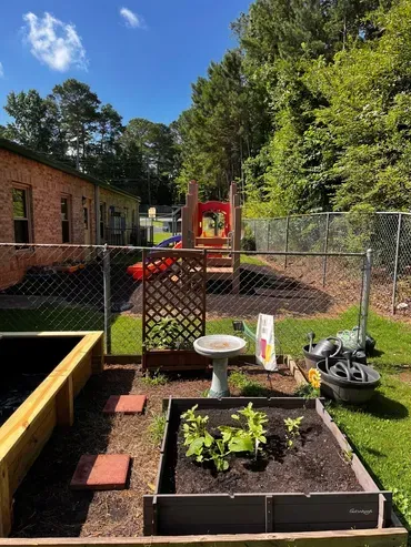 A garden with a bird bath and a playground in the background.