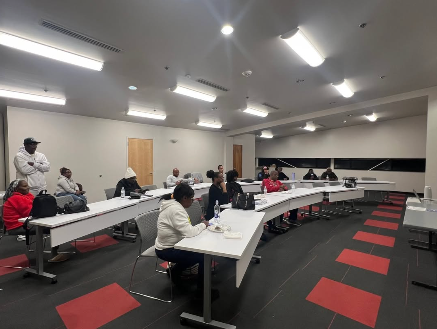 A group of people are sitting at long tables in a large room.