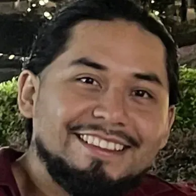 A man with a beard and long hair is smiling for the camera.