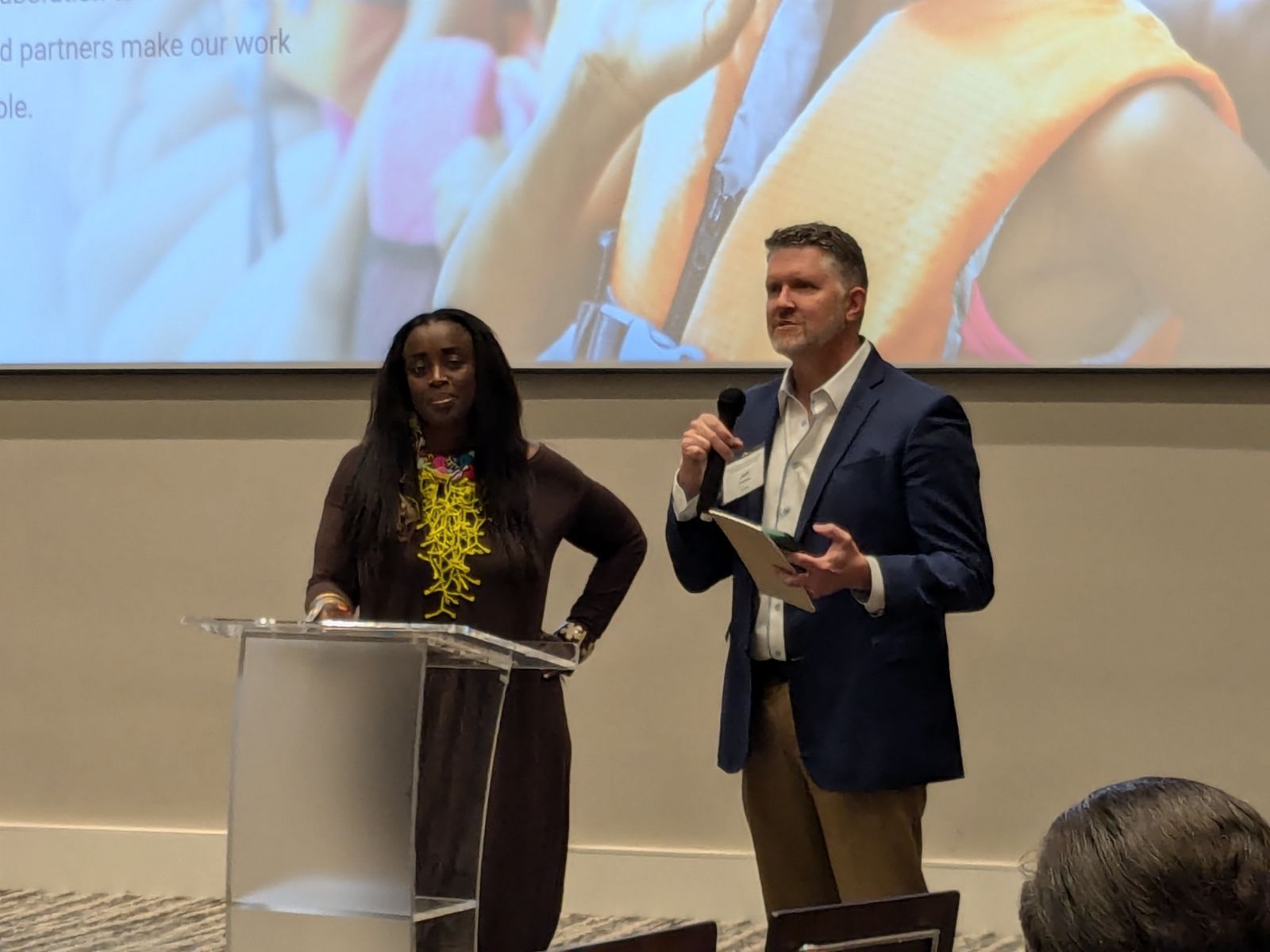 A man and a woman are standing at a podium giving a presentation.