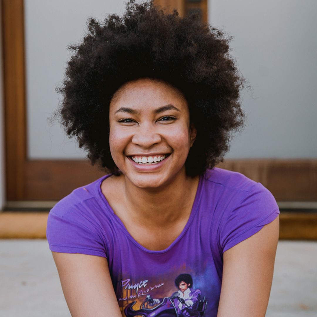 A woman wearing a purple shirt with prince on it