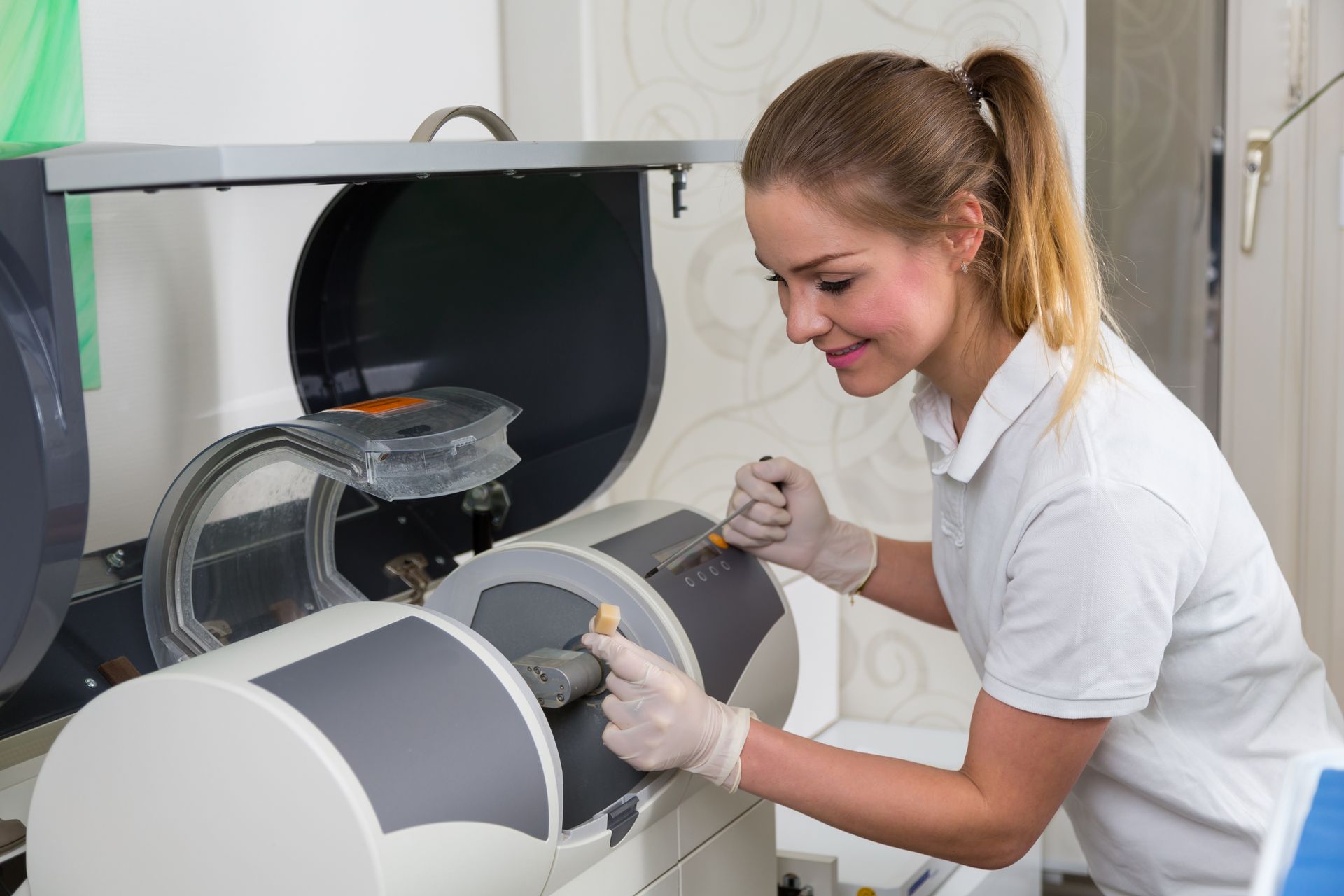 A woman is working on a machine in a dental office.