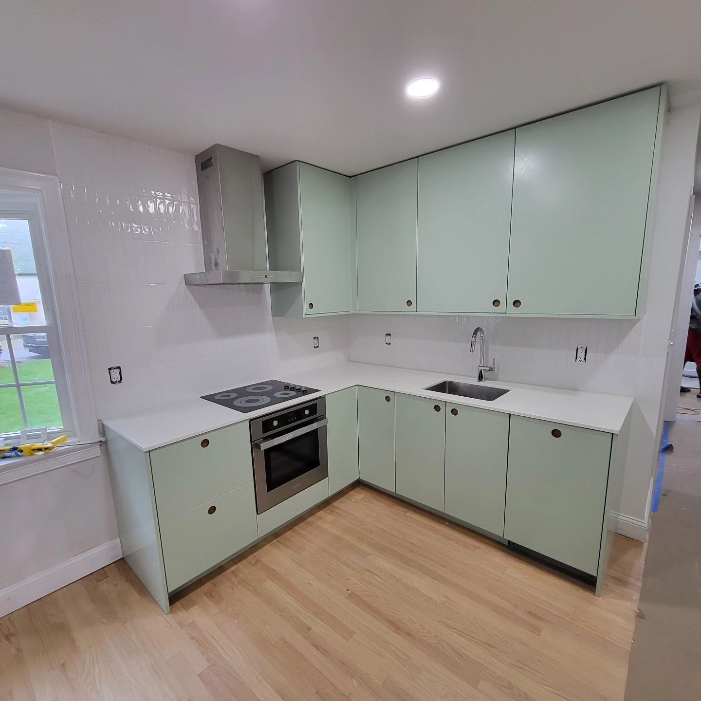 A kitchen with green cabinets and white counter tops