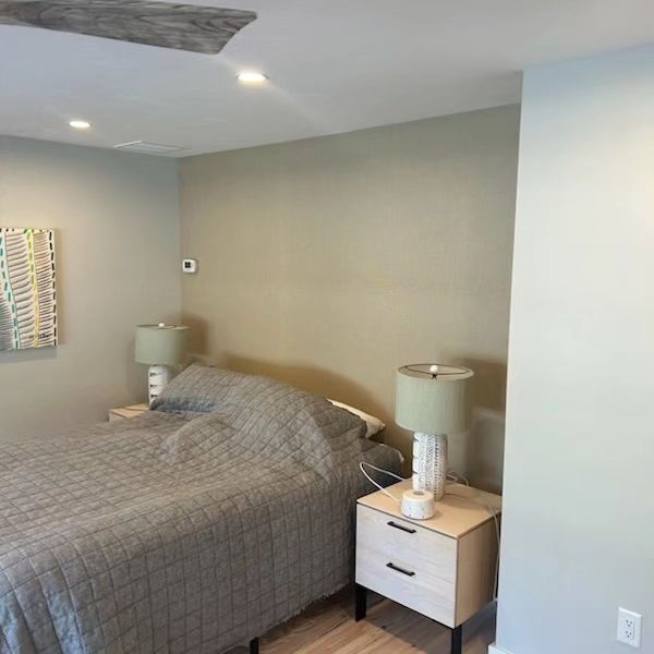 A bedroom with a bed , nightstand , lamps and a ceiling fan.