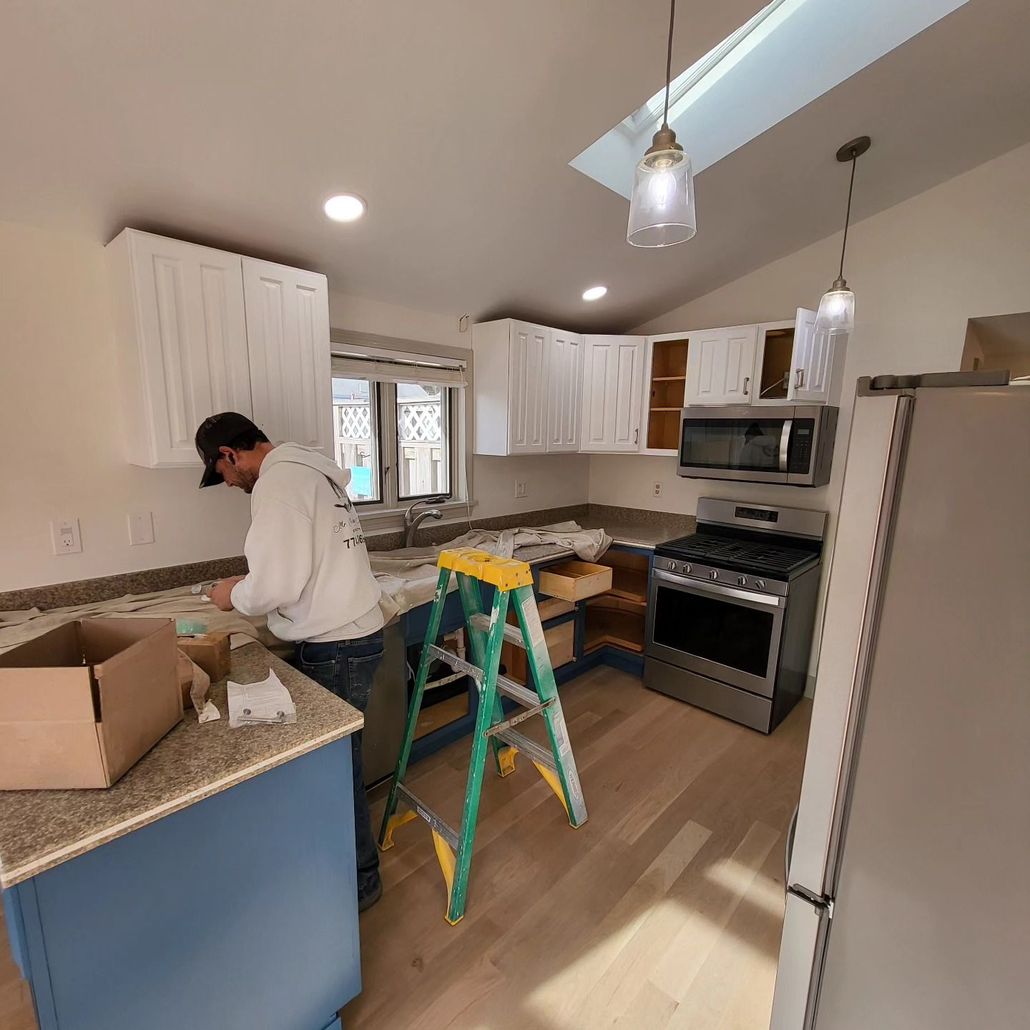 A man is standing in a kitchen next to a ladder.