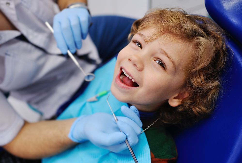 Little Boy Is Sitting In A Dental Chair While A Dentist Examines His Teeth — Byron Bay Dental in Byron Bay, NSW