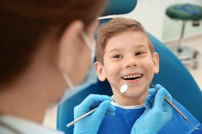 A Young Boy Is Sitting in A Dental Chair While a Dentist Examines His Teeth  — Byron Bay Dental in Byron Bay, NSW