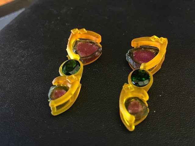 A pair of yellow and green earrings on a black surface