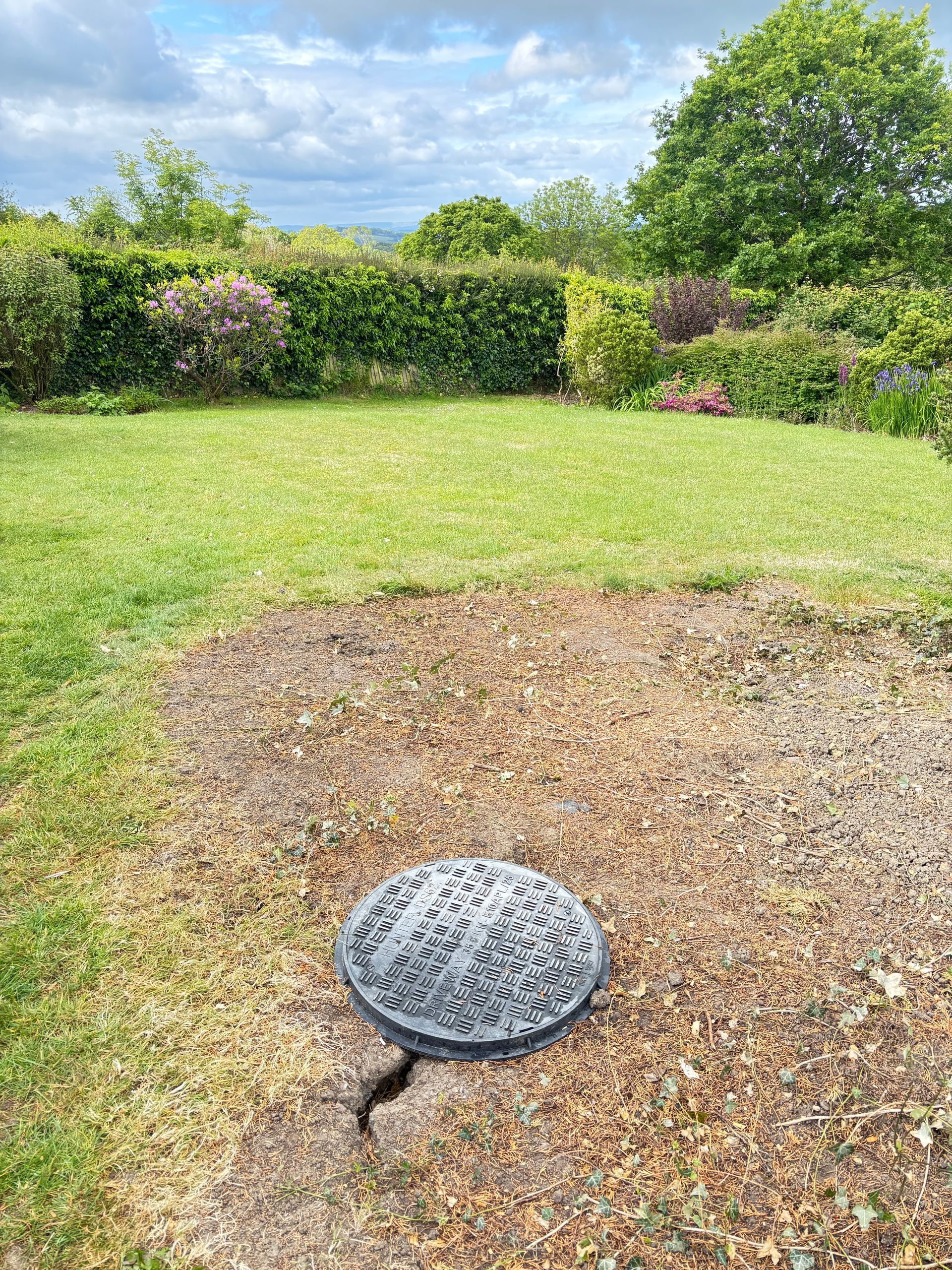 Concrete slab with rebar grid and level on top, framed by a raised border in a garden setting