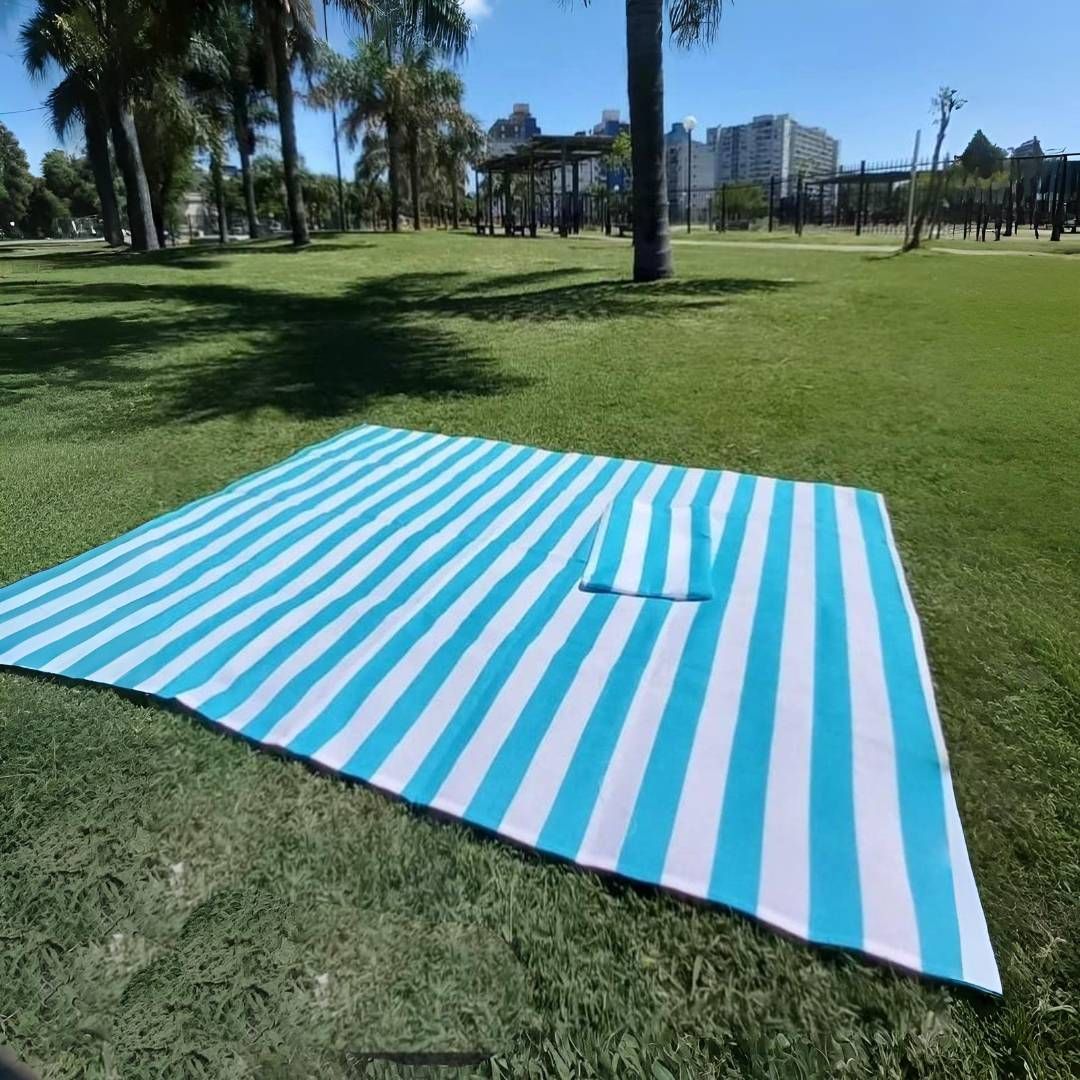 Manta de picnic a rayas azules y blancas sobre un césped en un parque.
