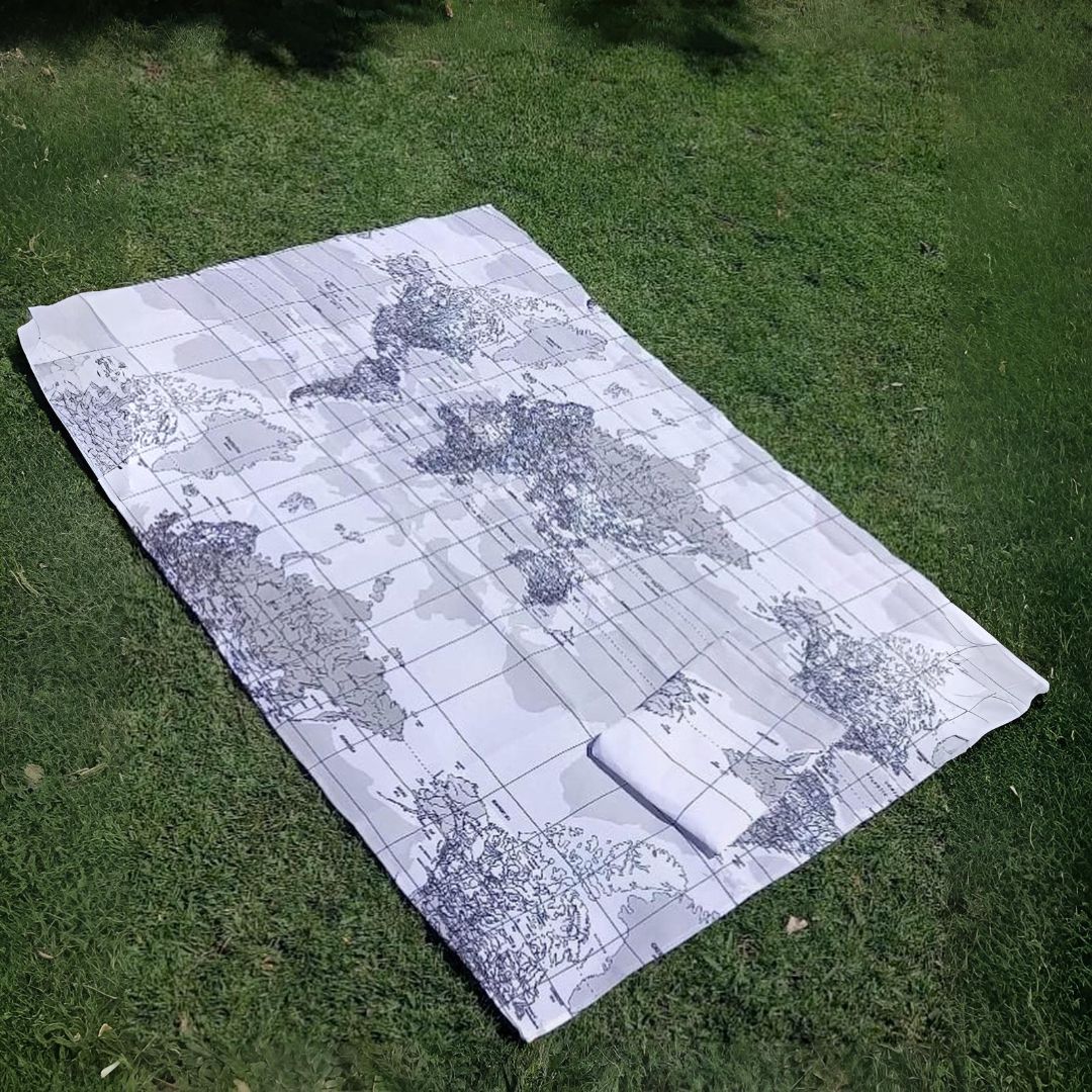 Manta de picnic sobre césped, diseño de mapa del mundo, enrollada en un extremo.
