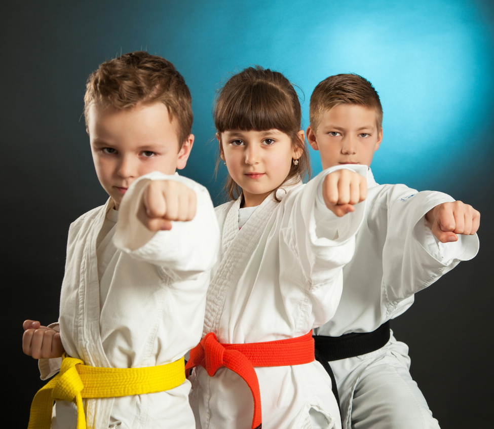 A boy and two girls are practicing karate together.