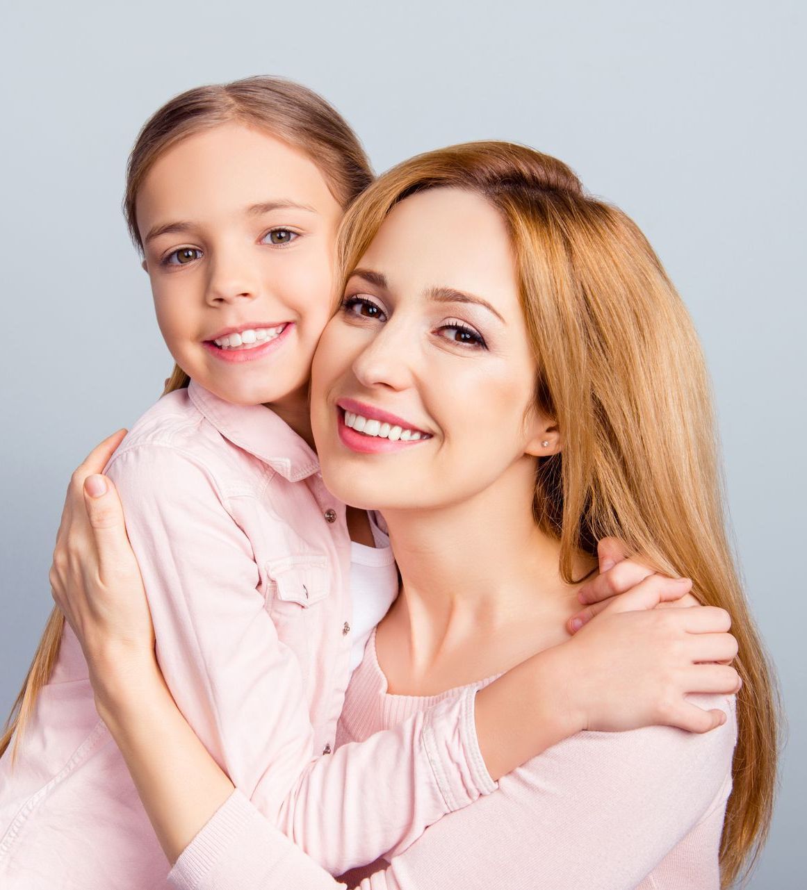 A woman and a little girl are hugging each other and smiling.