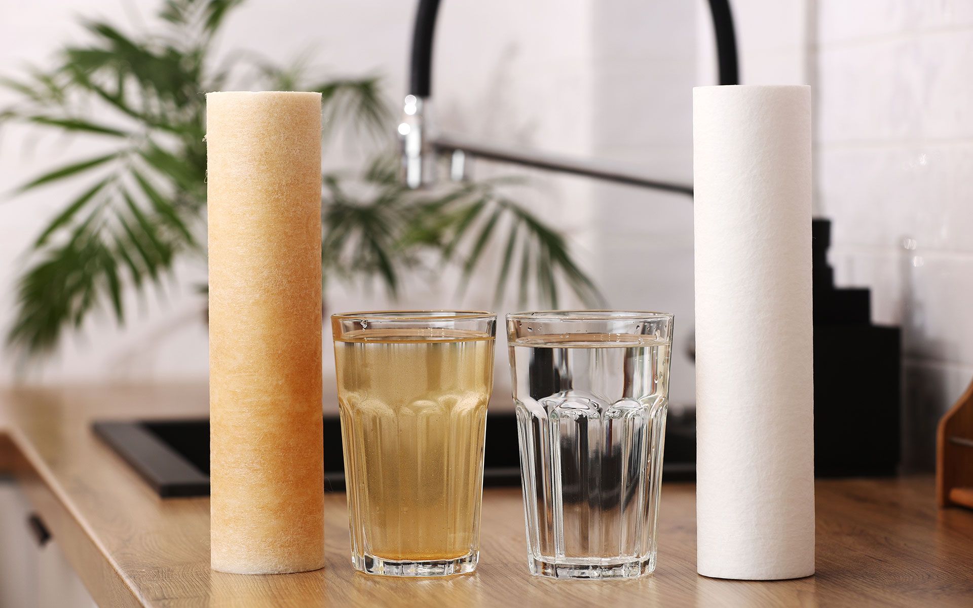 Two glasses of water are sitting on a kitchen counter next to a faucet.