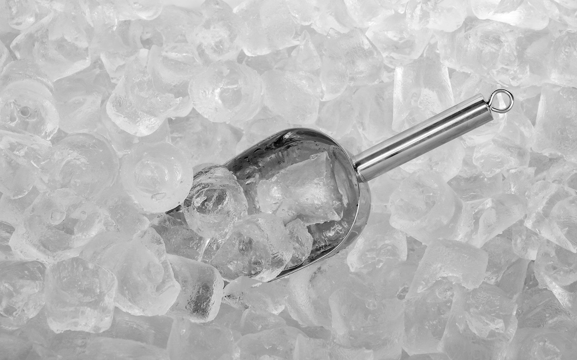 A scoop of ice is sitting on top of a pile of ice cubes.