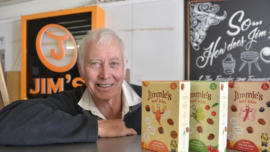 A man is standing in front of a sign that says Jim's Jerky