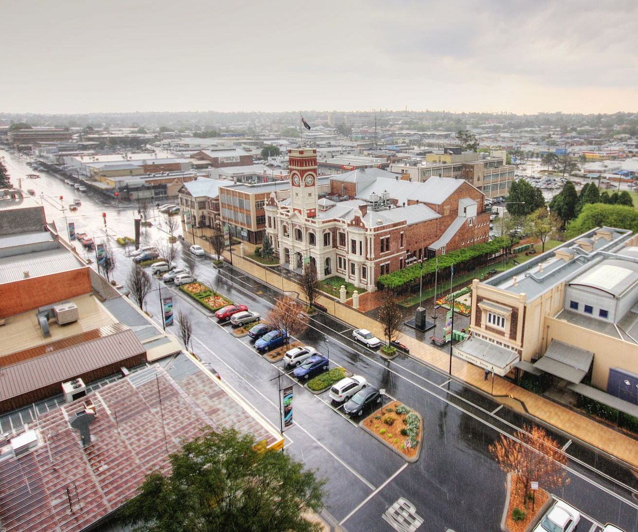 An aerial view of a city with a lot of cars parked on the side of the road.