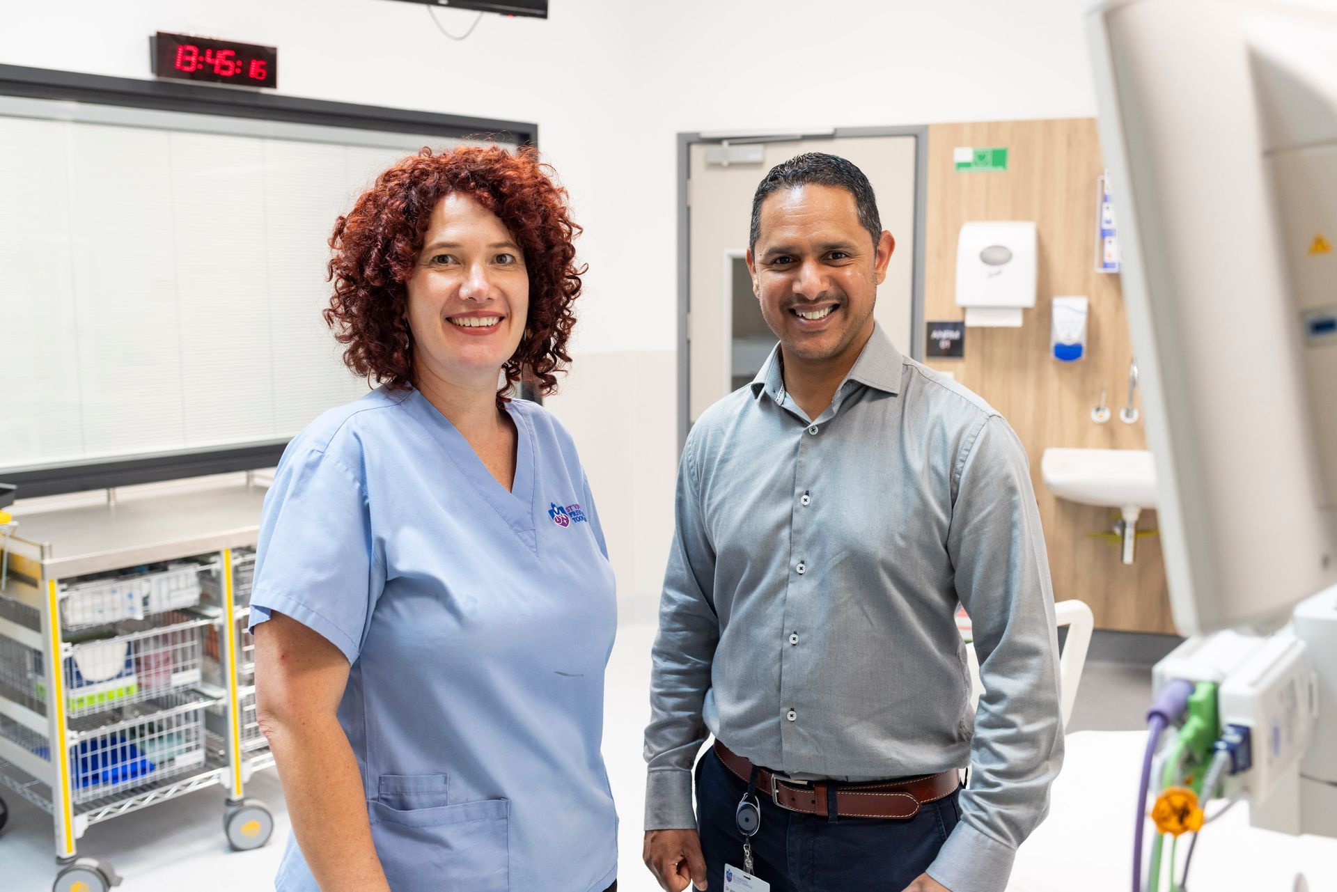 A man and a woman are standing next to each other in a hospital room.