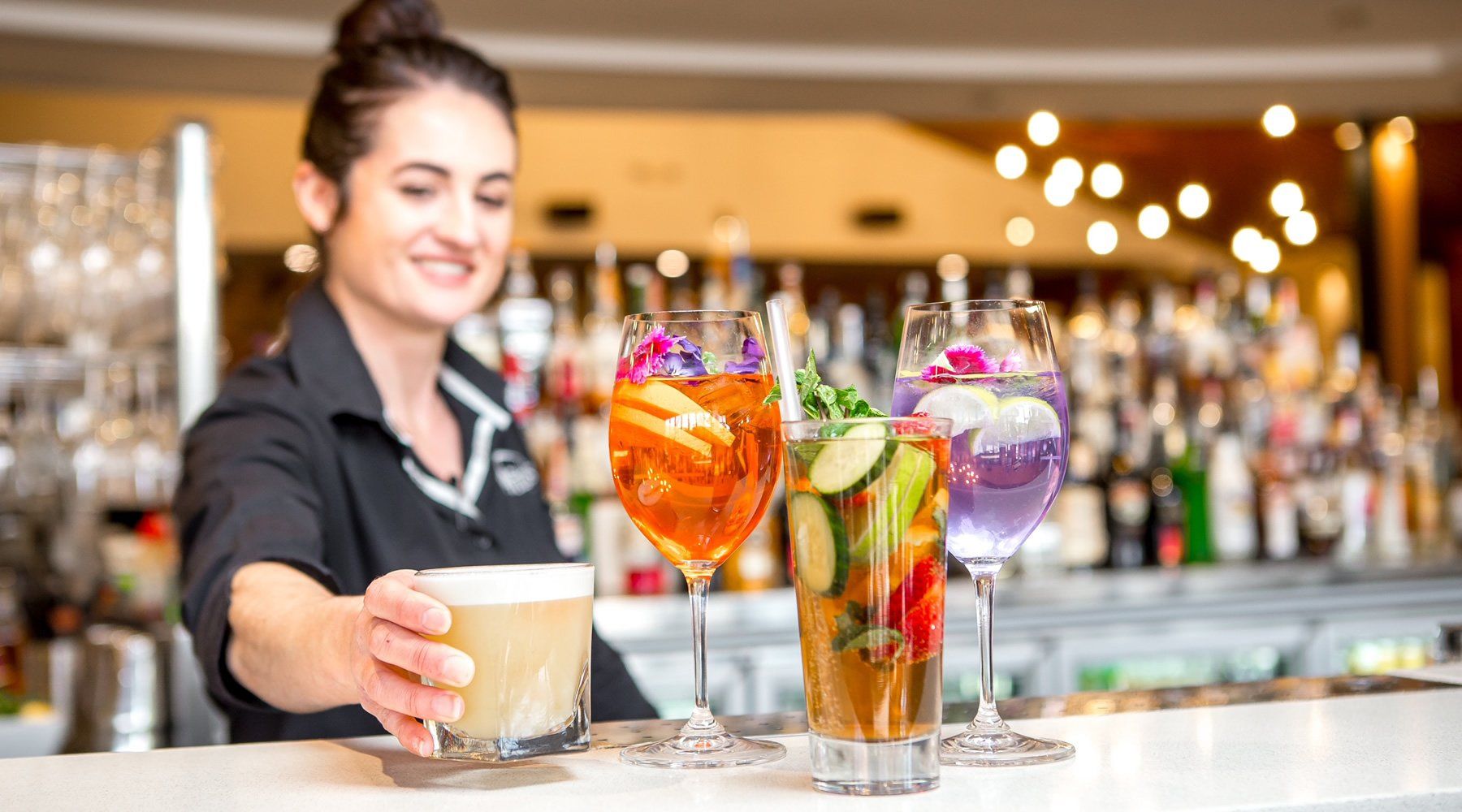 A woman is serving drinks at a bar.