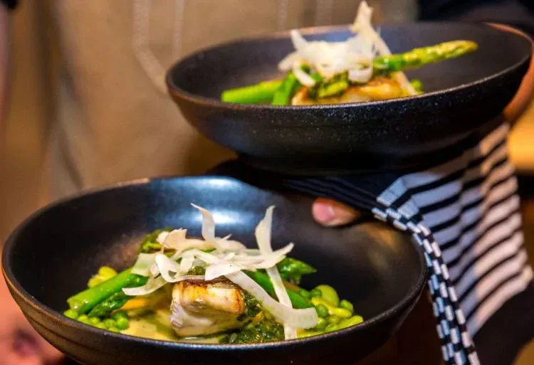 A person is holding two bowls of food in their hands.