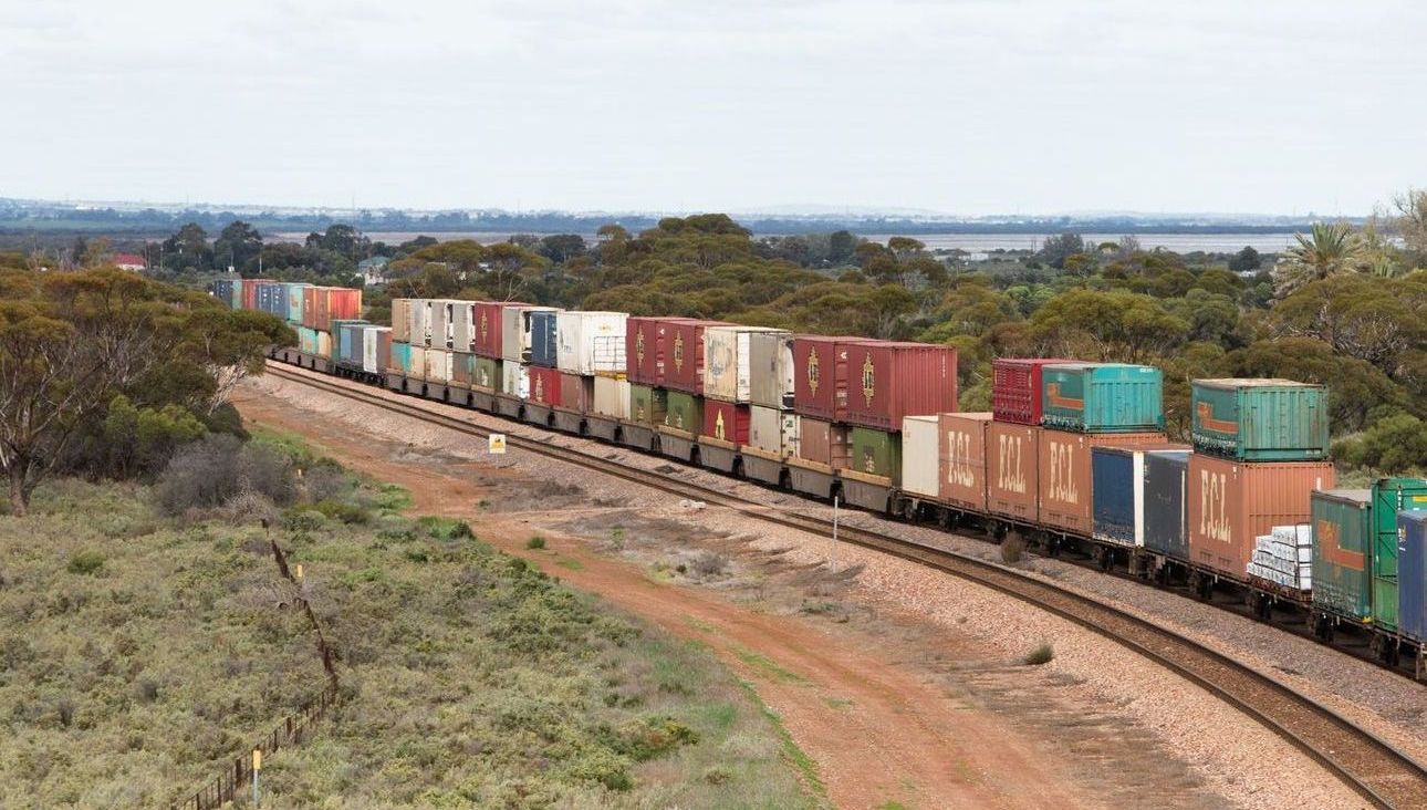 A train filled with containers is going down the tracks.