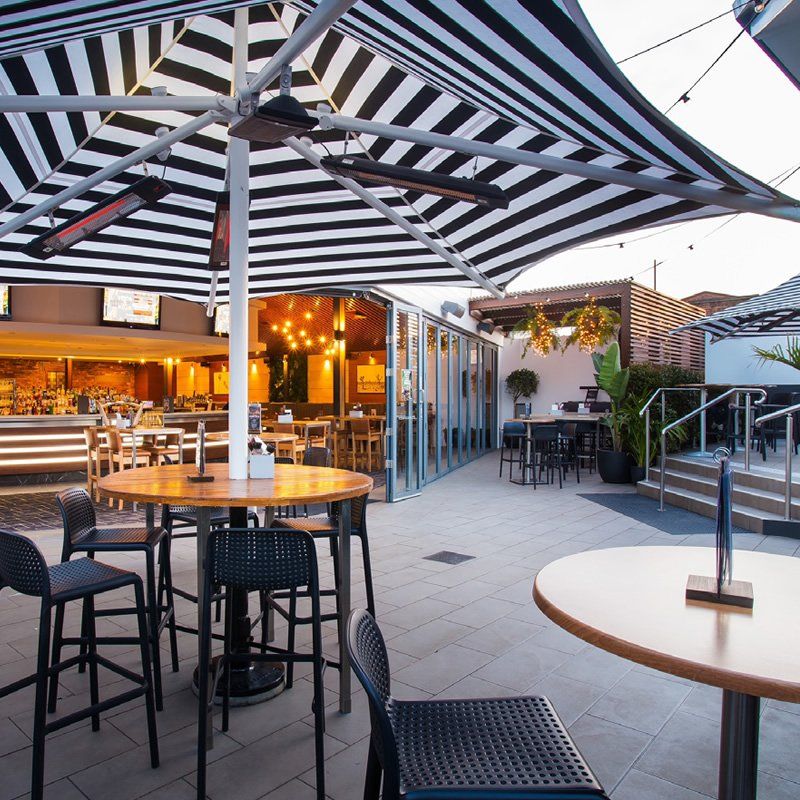 A restaurant with tables and chairs under striped umbrellas