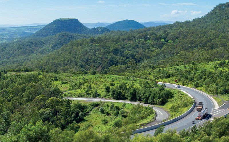 A road going through a forest with mountains in the background.