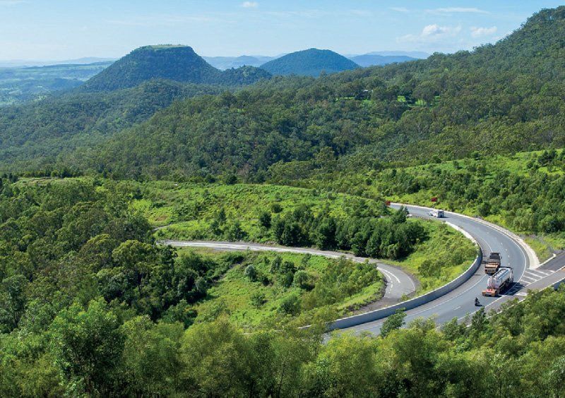 An aerial view of a winding road surrounded by trees and mountains.