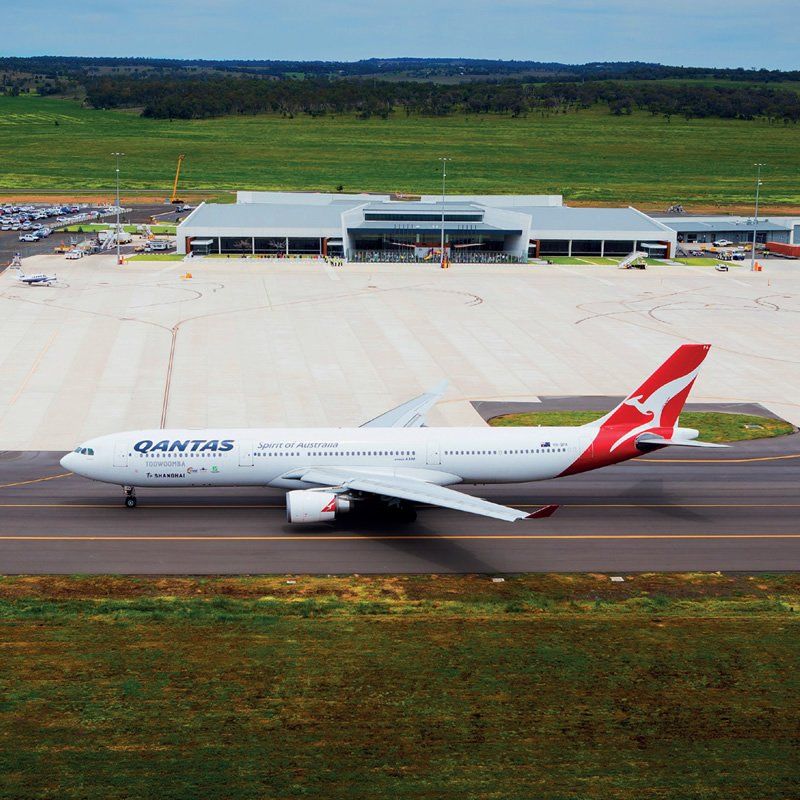 A Qantas airplane is on the runway at an airport