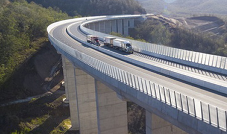 A truck is driving over a bridge on a highway.