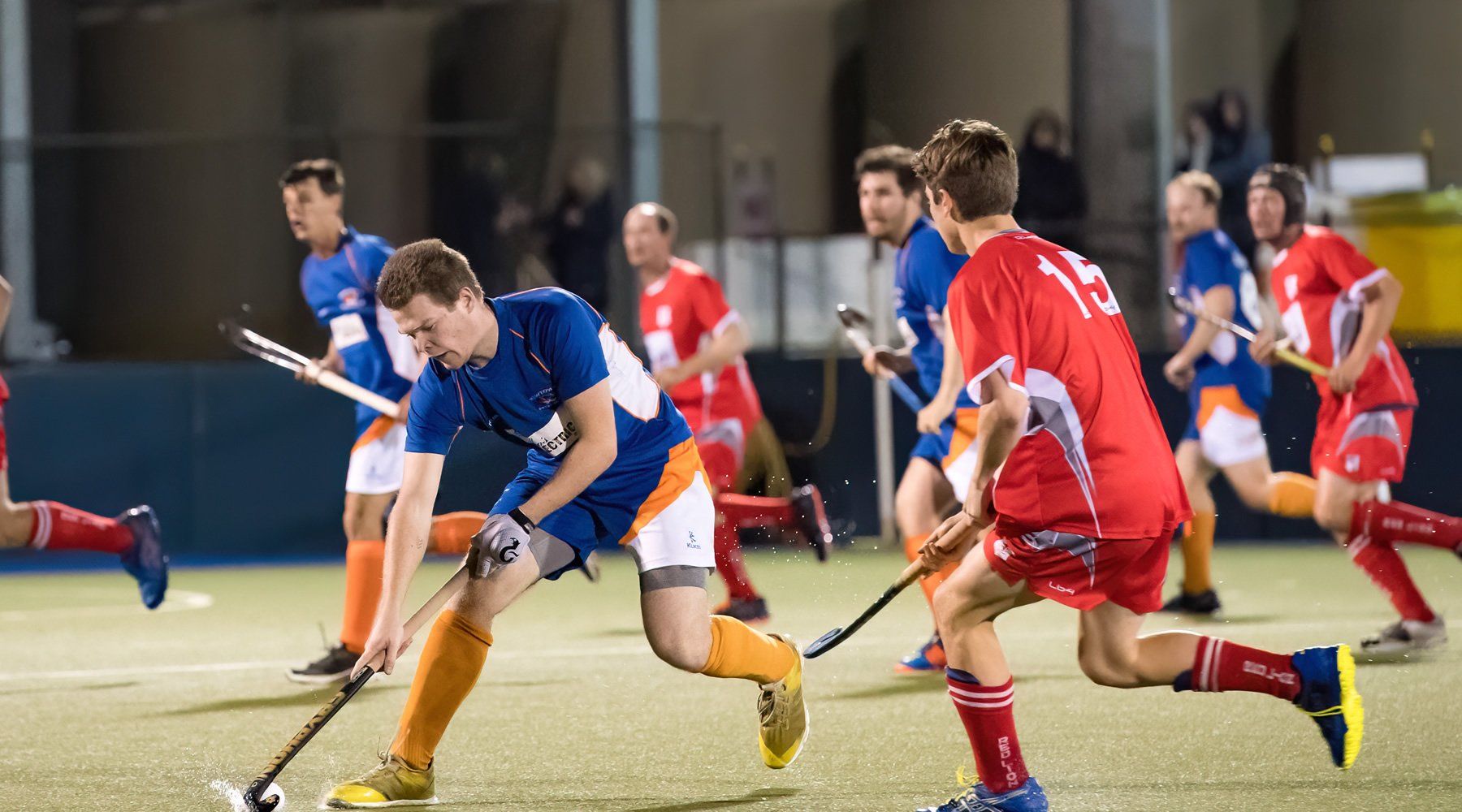 A group of men are playing field hockey on a field.
