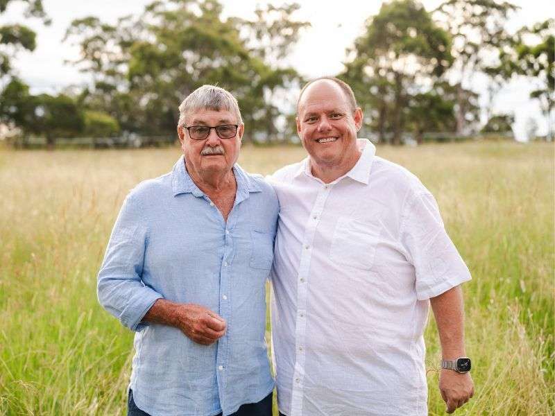 Two men are standing next to each other in a field.