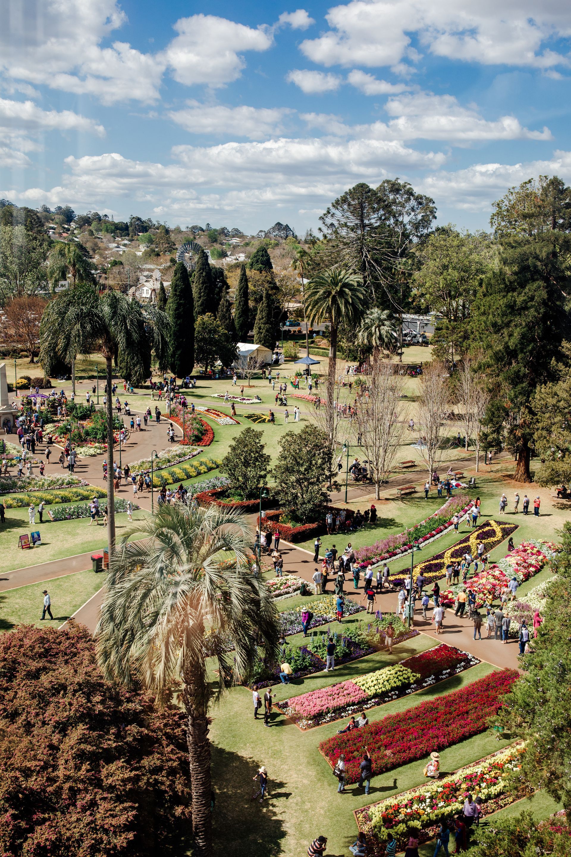 An aerial view of a park filled with lots of flowers and people.