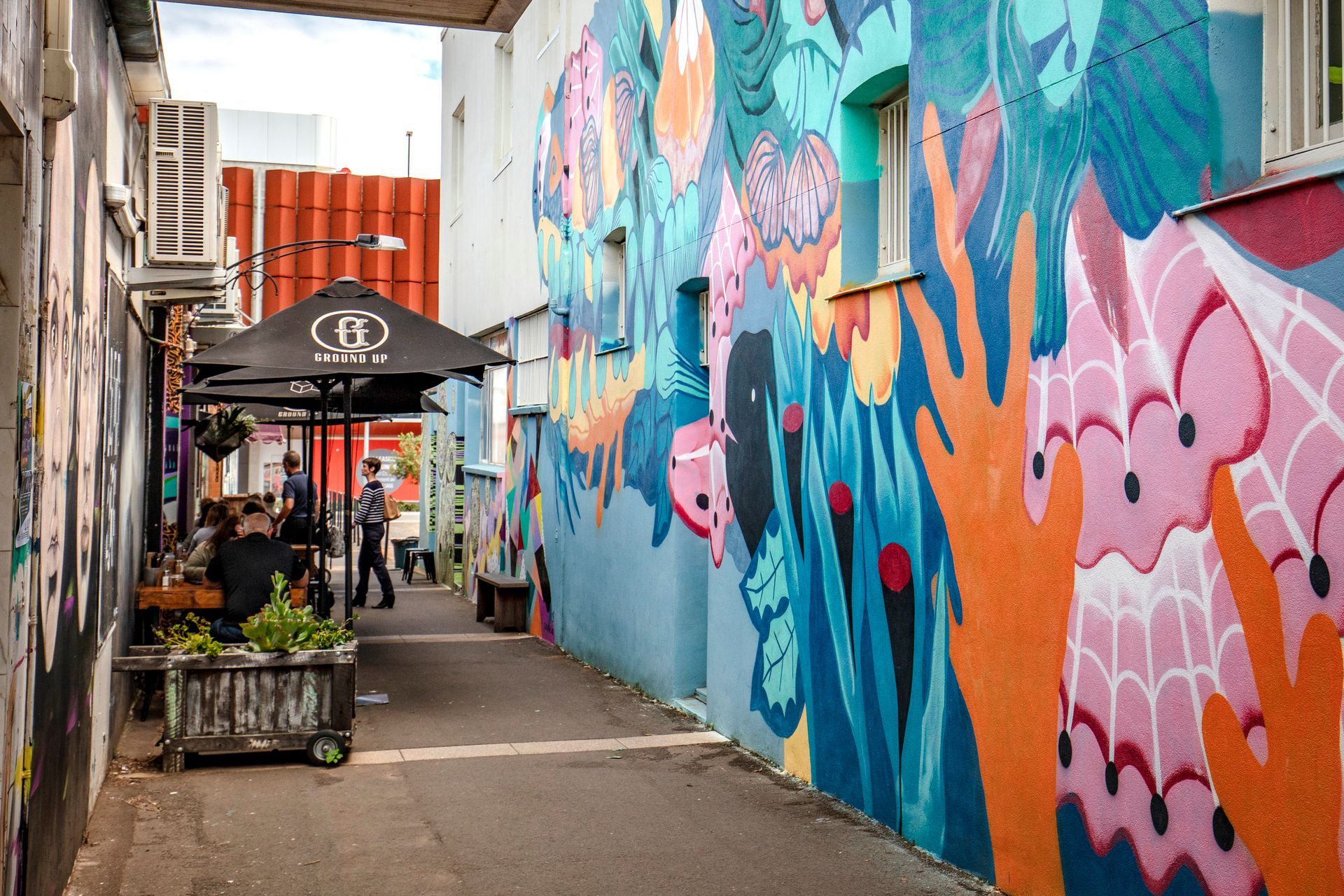 A narrow alleyway with a colorful mural on the side of a building.