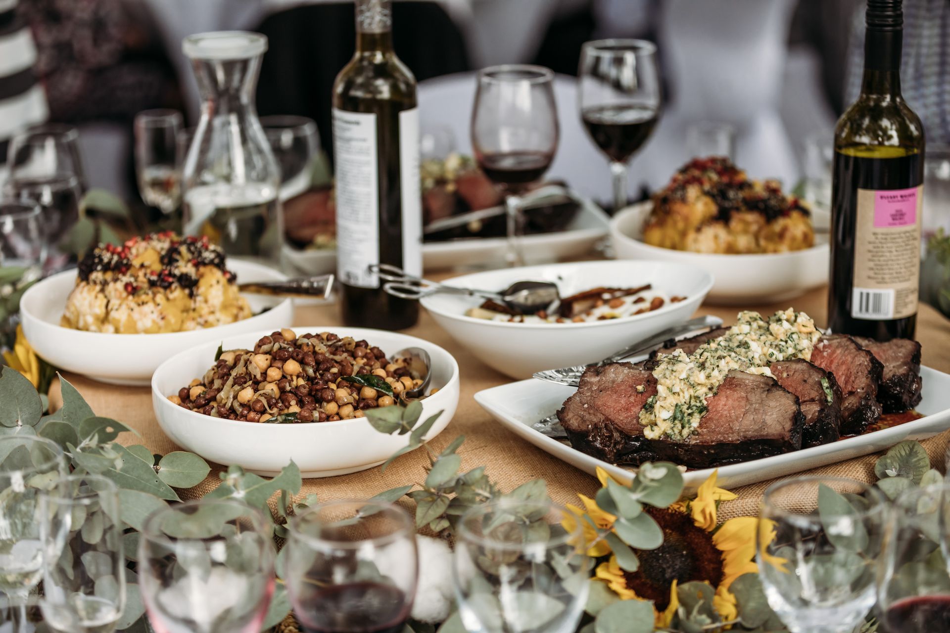 A table topped with plates of food and wine glasses.