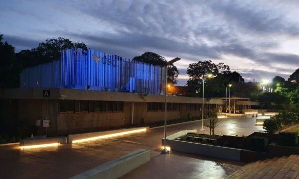 A large building is lit up with blue lights at night.