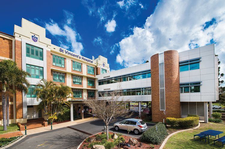 A large hospital building with a lot of windows and a car parked in front of it.