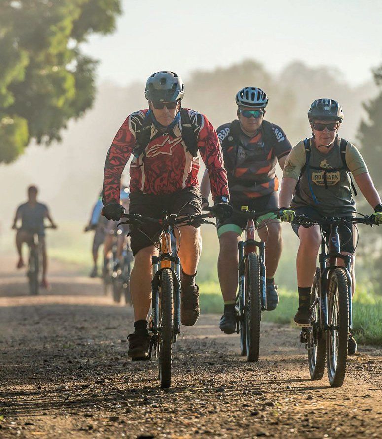 A group of people are riding bicycles down a dirt road.