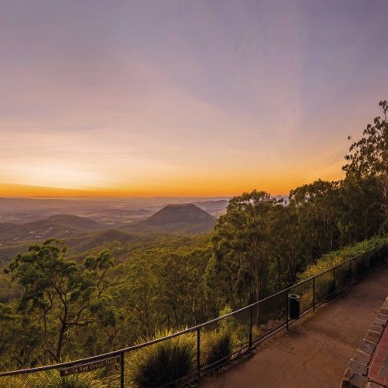A view of a sunset over a mountain range from a balcony.