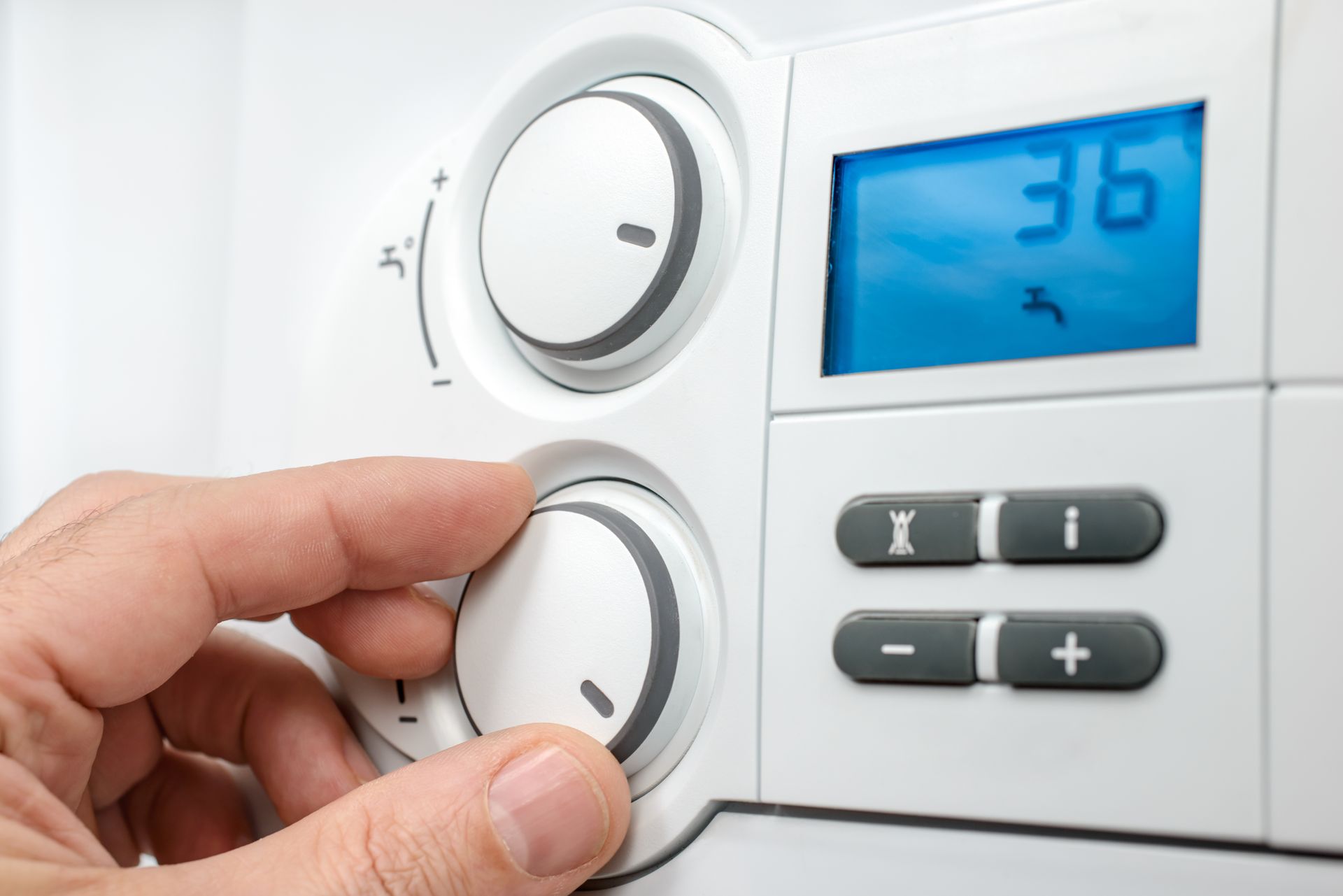 A person is adjusting the temperature on a thermostat.