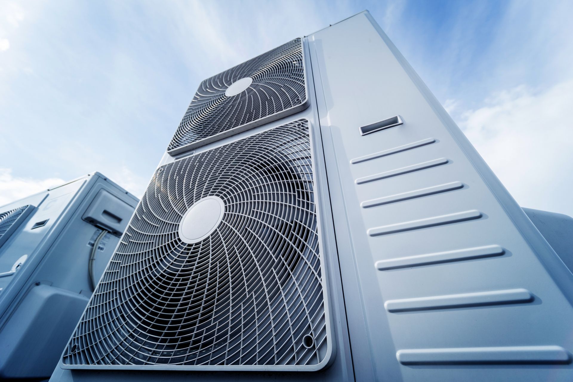 A row of air conditioners are stacked on top of each other on top of a building.