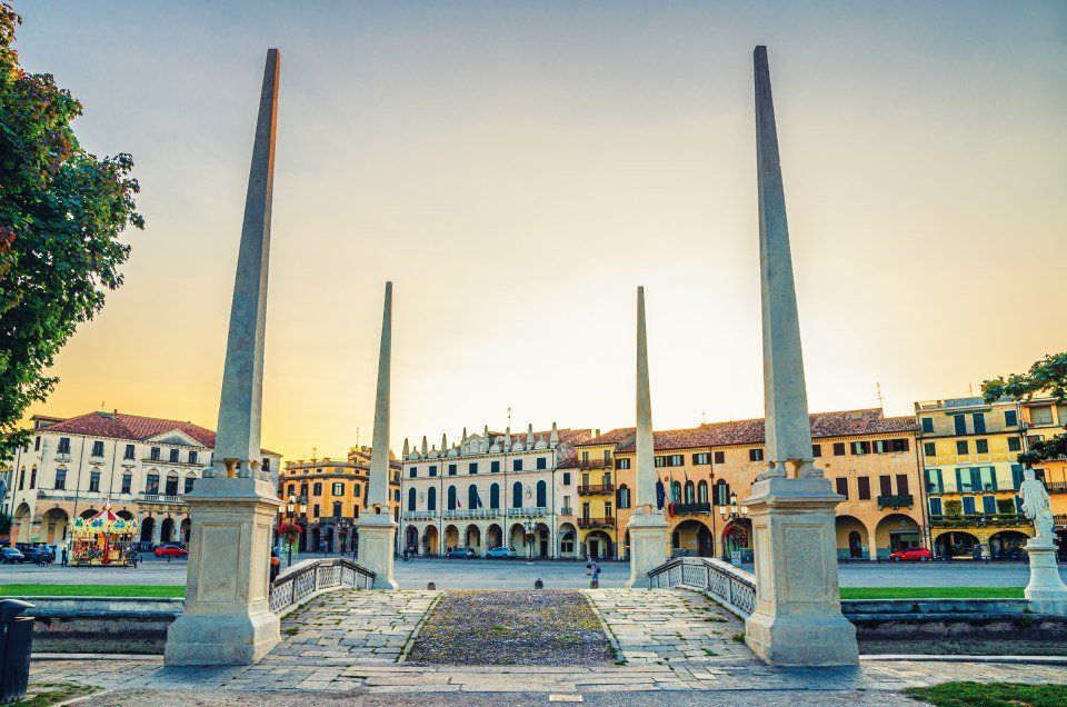 Prato della Valle a Padova al tramonto. Gli edifici fiancheggiano la piazza con colori caldi.