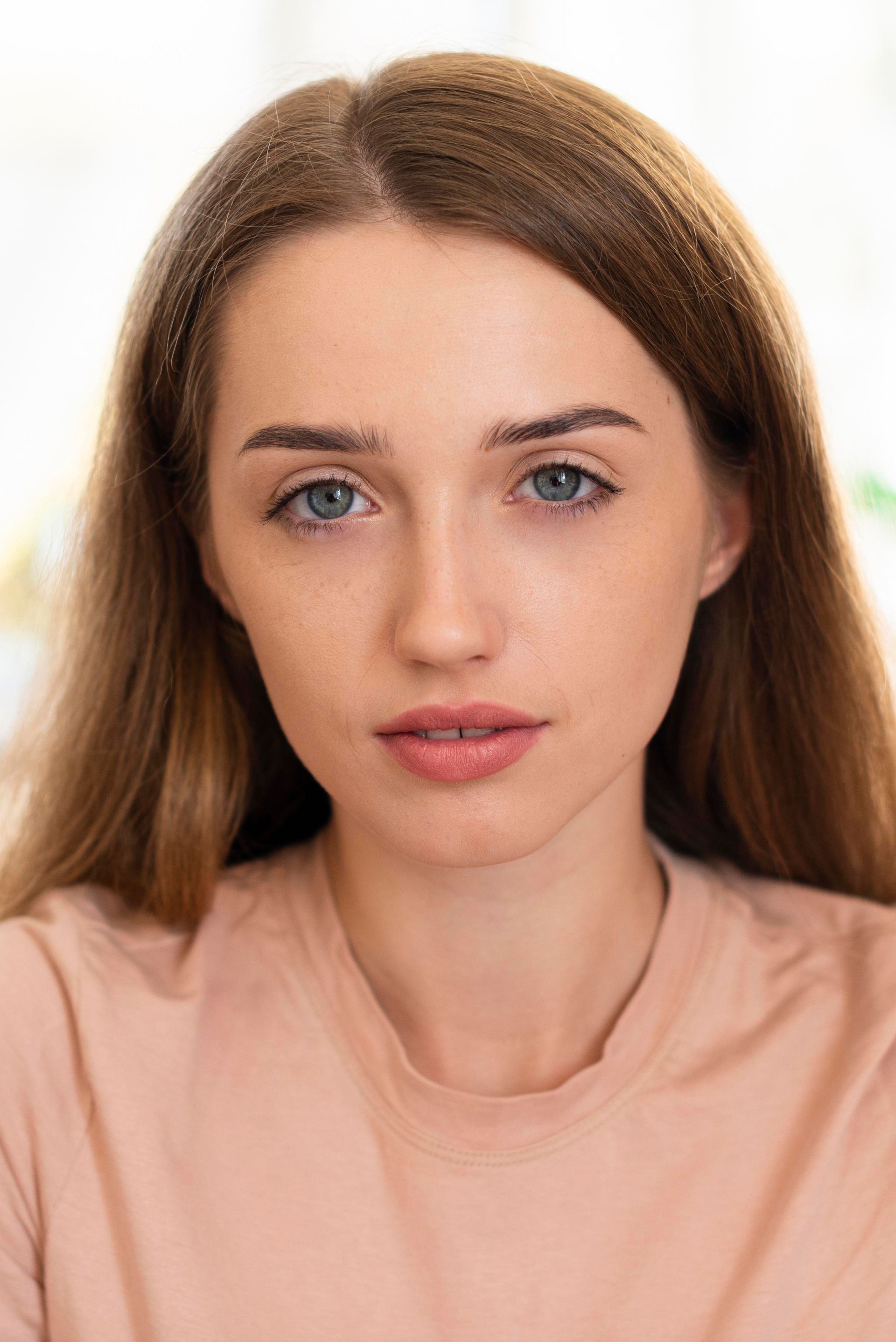 A young woman with long hair and blue eyes is looking at the camera.