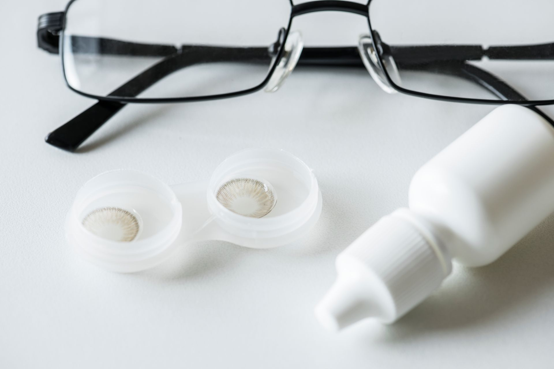 A pair of glasses and a bottle of contact lens solution