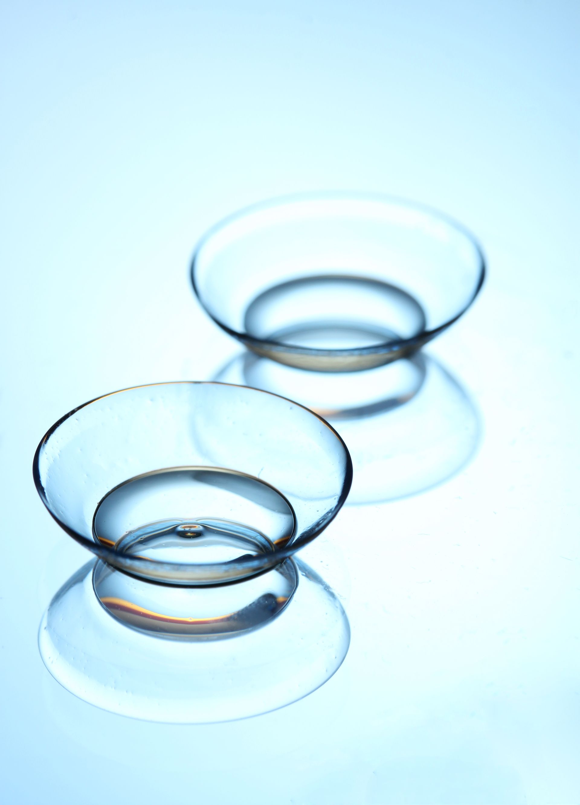 A pair of contact lenses on a blue surface