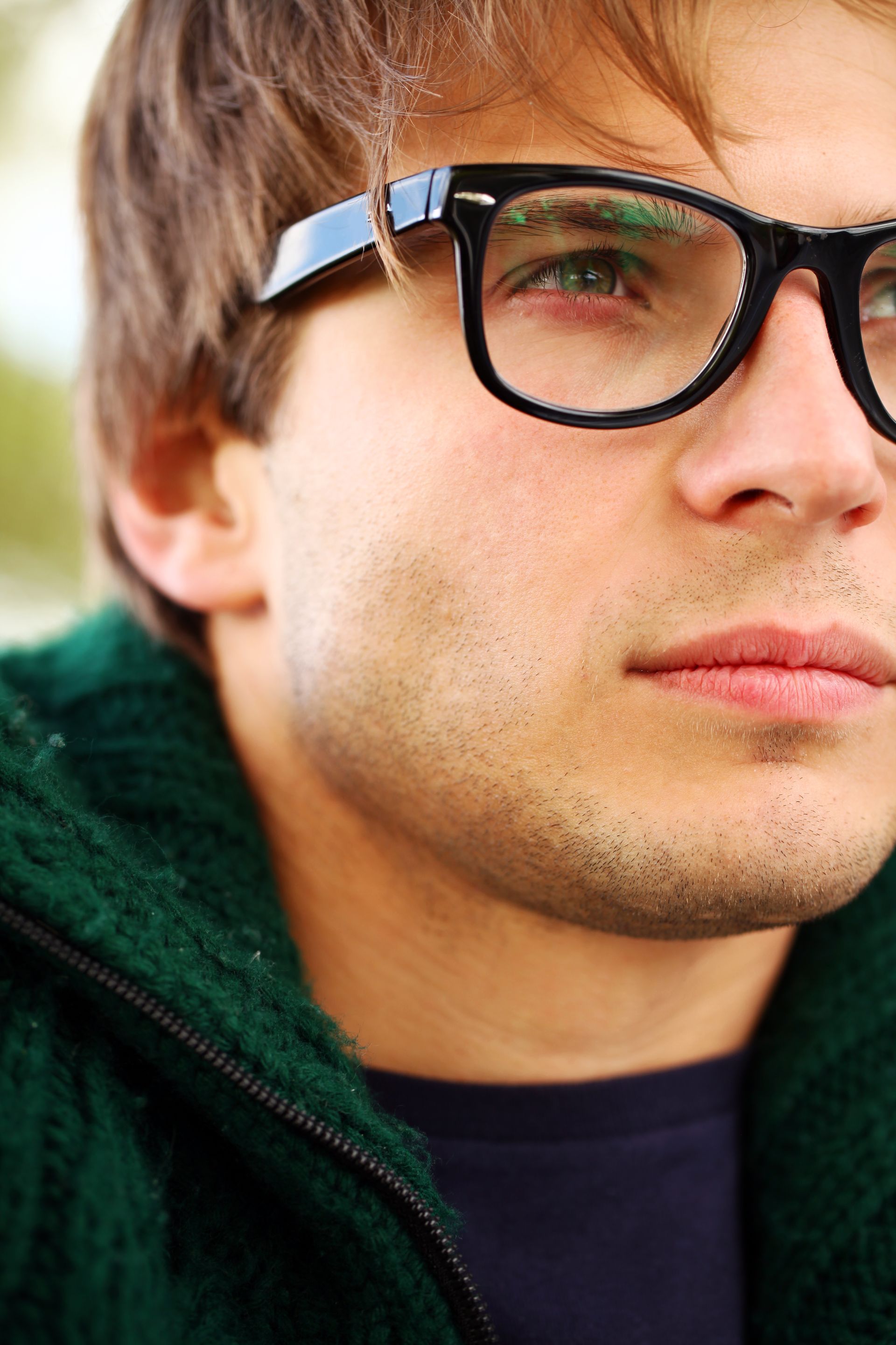 A close up of a man wearing glasses and a green jacket