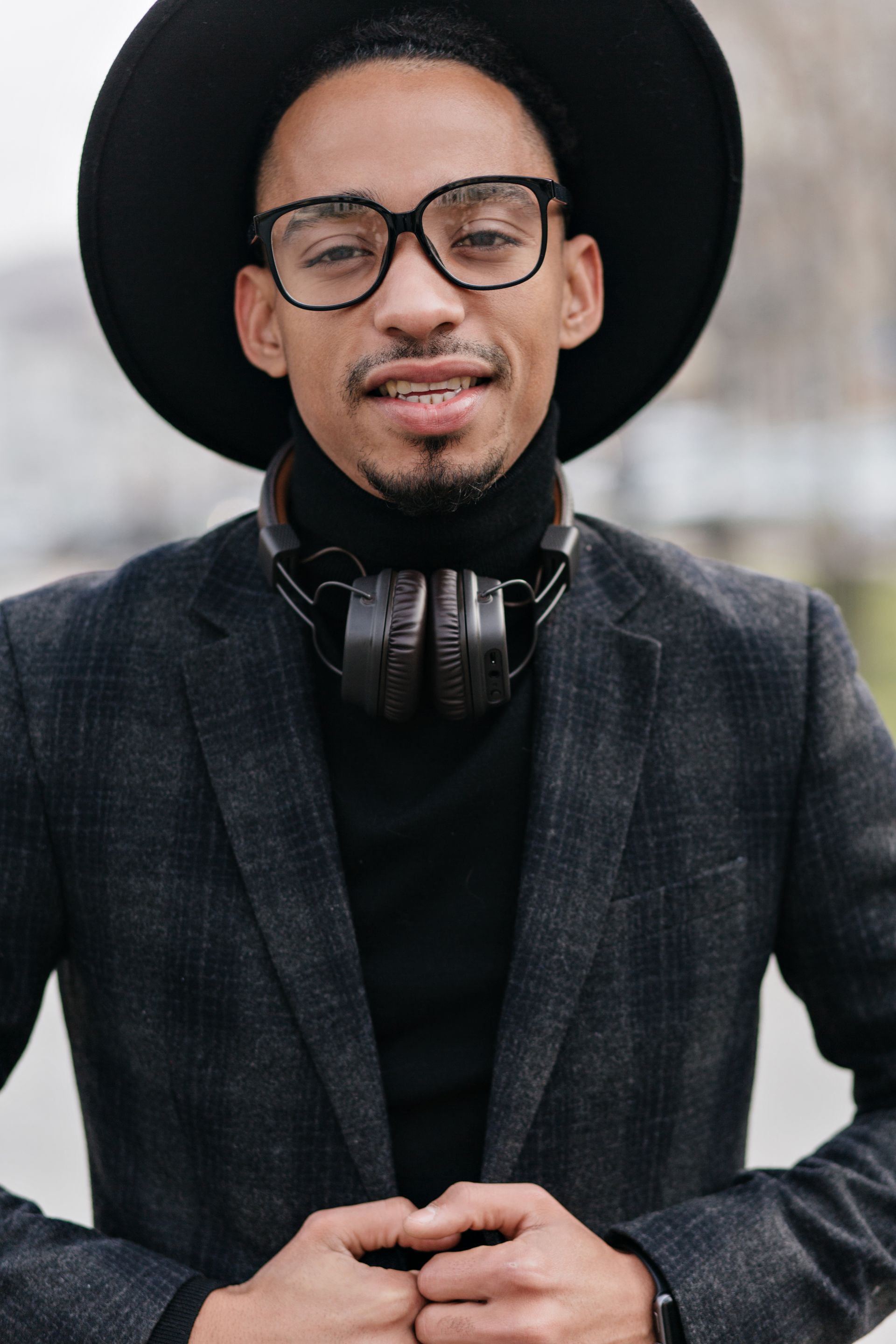 A man wearing a hat and headphones around his neck.