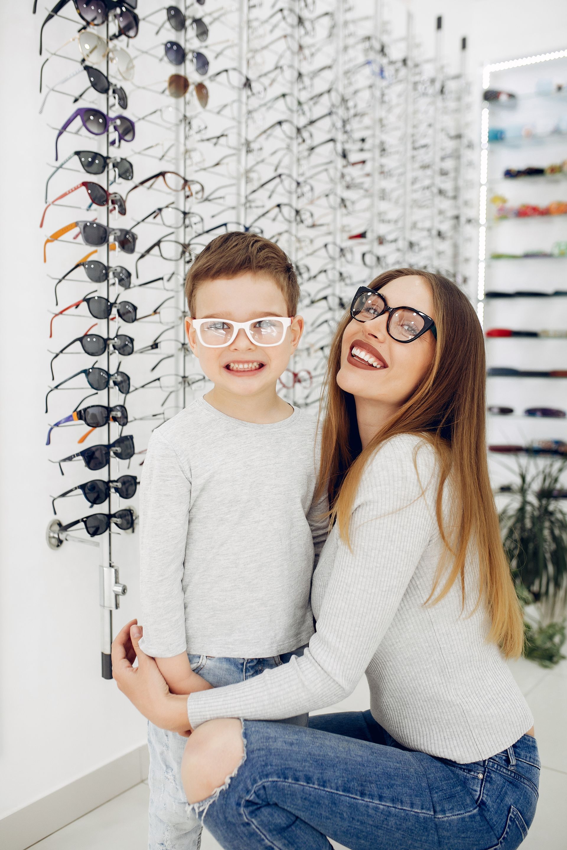 A woman and a boy wearing glasses in an optical shop.